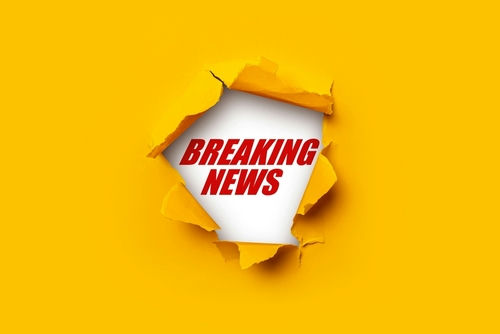 Breaking News text on yellow torn paper background.