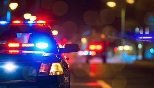 Police car with flashing lights parked on a city street at night