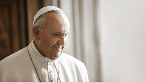 Pope Francis smiling in a white robe and zucchetto