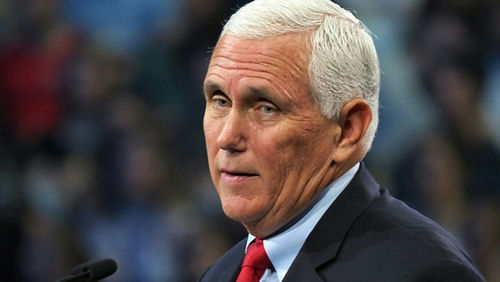 man with short white hair speaking at a podium